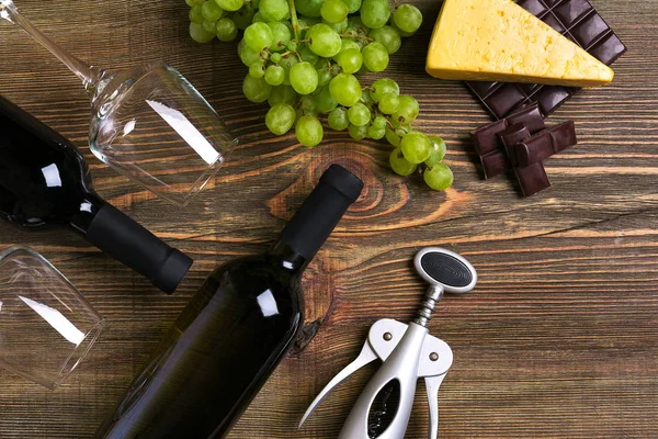 Kırmızı ve beyaz şarap şişeleri, üzüm, peynir ve ahşap masa üzerinde gözlük. Kopya alanı ile Üstten Görünüm
