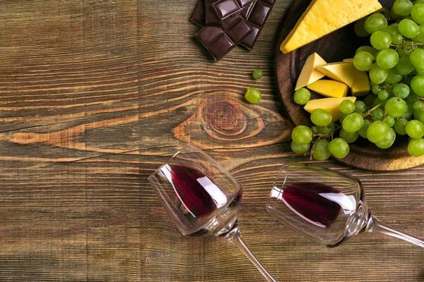 Dois copos de vinho tinto, queijo, uvas verdes e chocolate, vista superior — Fotografia de Stock