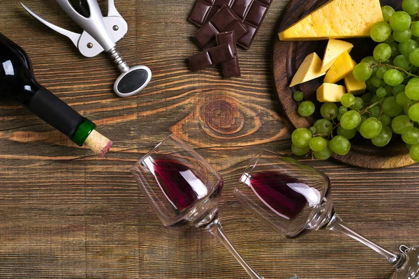 Kırmızı şarap şişesi, üzüm, peynir ve ahşap masa üzerinde gözlük. Kopya alanı ile Üstten Görünüm