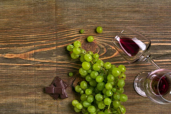 Ahşap bir masaya izole olgun üzüm ve şarap gözlük