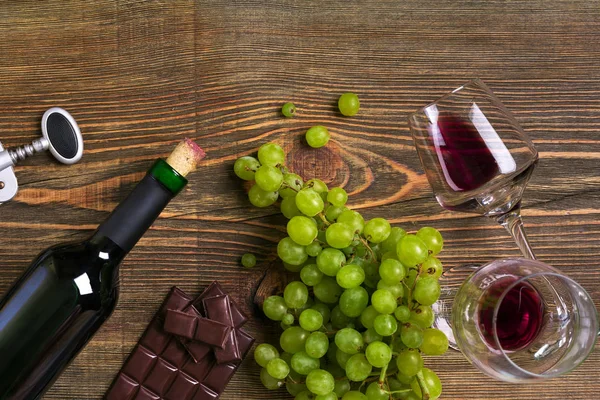 Garrafa de vinho tinto, uva, queijo e copos sobre mesa de madeira. Vista superior com espaço de cópia — Fotografia de Stock