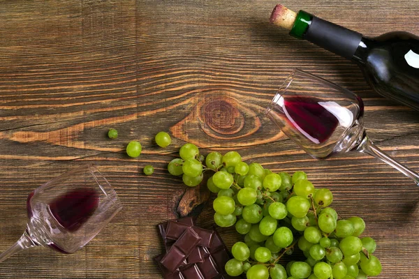 Garrafa de vinho tinto, uva, chocolate e copos sobre mesa de madeira. Vista superior com espaço de cópia — Fotografia de Stock