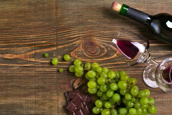 Dois copos, garrafa de vinho tinto e uva em uma mesa de madeira — Fotografia de Stock