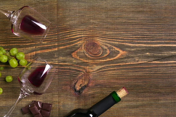Dois copos, garrafa de vinho tinto e uva em uma mesa de madeira — Fotografia de Stock