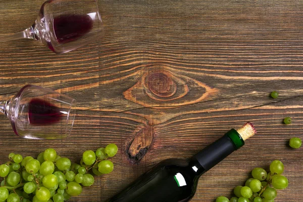 Garrafa de vinho tinto, uva e copos sobre mesa de madeira. Vista superior com espaço de cópia — Fotografia de Stock