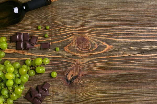 Flasche Wein und reife Trauben auf Holzgrund — Stockfoto