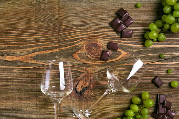 Dois copos de vinho tinto, uvas verdes e chocolate, vista superior — Fotografia de Stock