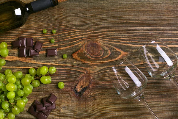 Dois copos, garrafa de vinho branco e uva em uma mesa de madeira — Fotografia de Stock