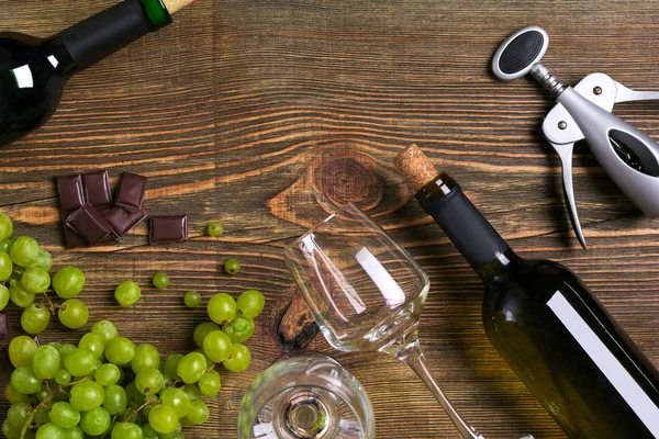Beyaz şarap şişesi, üzüm, çikolata ve ahşap masa üzerinde gözlük. Kopya alanı ile Üstten Görünüm