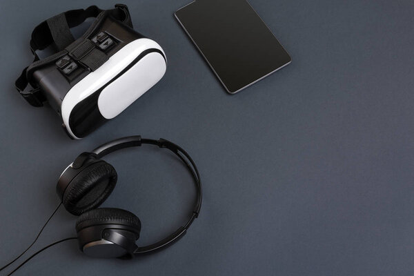 Virtual reality glasses and tablet with headphones on a gray background. Top view — Stock Photo, Image