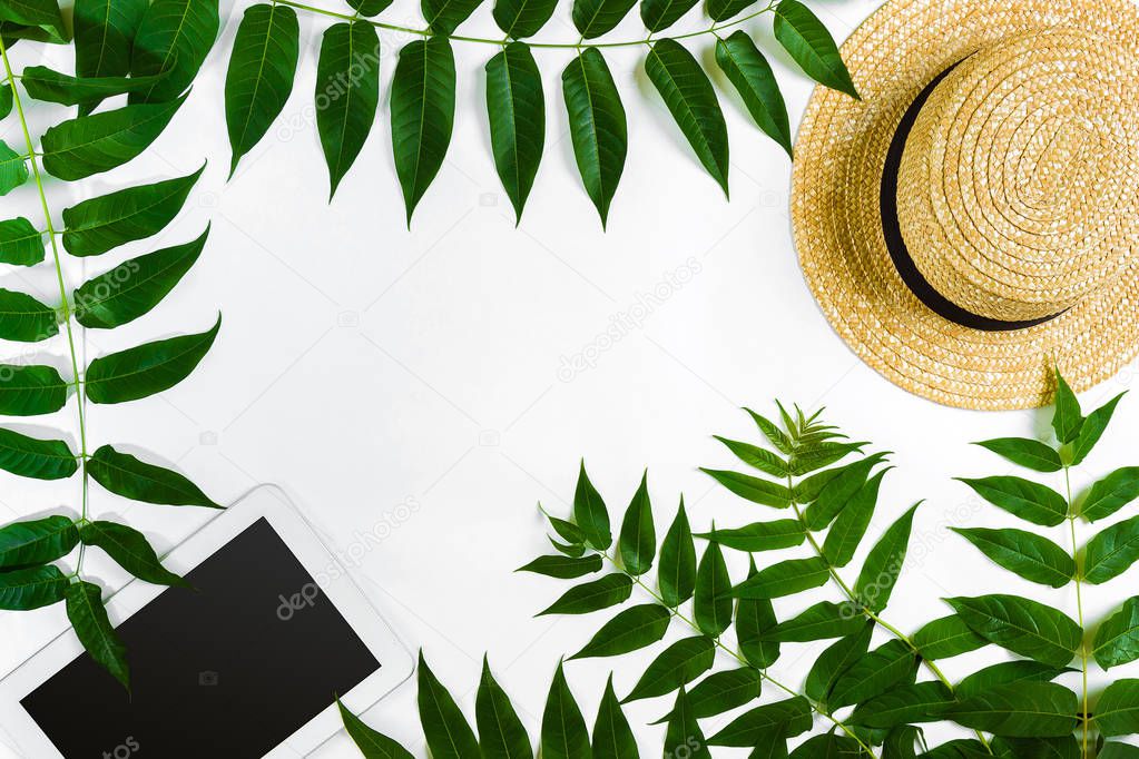 Green leaf branches, tablet and straw haton white background. flat lay, top view.