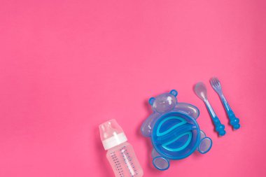 Kaşık ve çatal pink izole ile bebek şişe ve mavi plaka. Üstten Görünüm