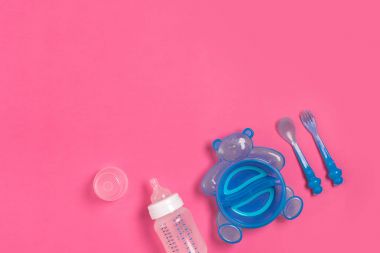 Mavi plaka bir ayı, bir şişesi, bıçak ve pembe tablo kaşık şeklinde. Çocuk yemek vakti. Üstten Görünüm