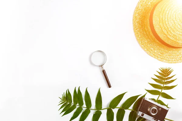 Straw hat with green leaves and old camera on white background, Summer background. Top view. Sun flare — Stock Photo, Image