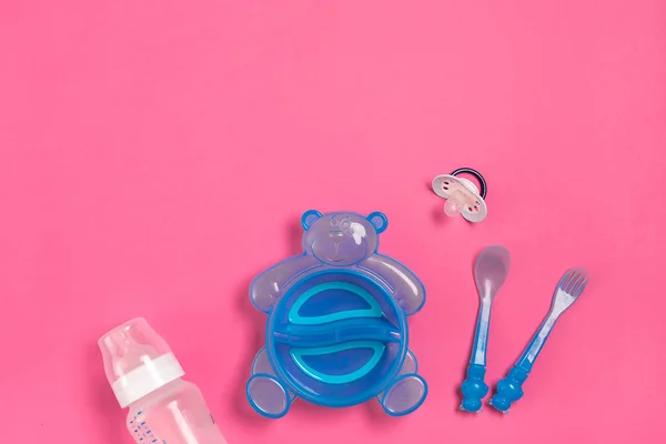 Blue plate in the form of a bear, a bottle, knife and spoon on pink table. Children dinner time. Top view — Stock Photo, Image