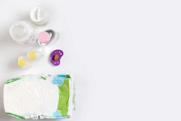 Babies goods diaper, baby powder, cream, shampoo, oil on white background with copy space. Top view or flat lay. — Stock Photo, Image