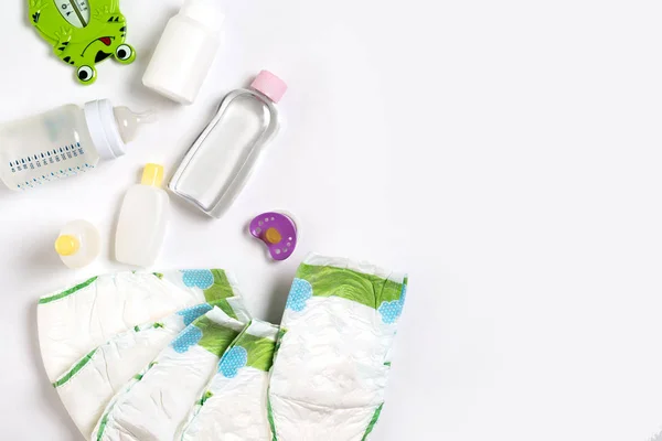 Babies goods diaper, baby powder, cream, shampoo, oil on white background with copy space. Top view or flat lay. — Stock Photo, Image