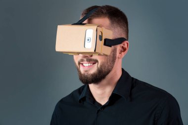 Gri arka plan üzerinde yeni bir sanal gerçeklik kulaklık kullanan adam