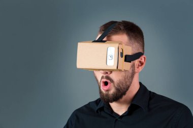 Gri arka plan üzerinde yeni bir sanal gerçeklik kulaklık kullanan adam