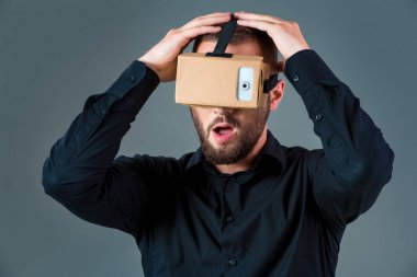 Gri arka plan üzerinde yeni bir sanal gerçeklik kulaklık kullanan adam