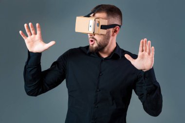 Gri arka plan üzerinde yeni bir sanal gerçeklik kulaklık kullanan adam