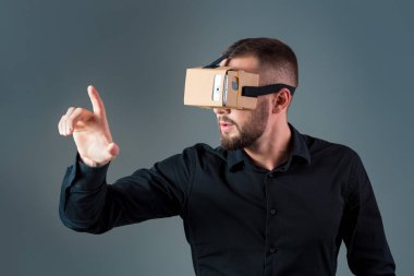 Gri arka plan üzerinde yeni bir sanal gerçeklik kulaklık kullanan adam