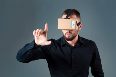 Gri arka plan üzerinde yeni bir sanal gerçeklik kulaklık kullanan adam