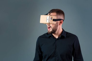 Gri arka plan üzerinde yeni bir sanal gerçeklik kulaklık kullanan adam