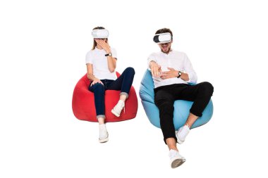 Sanal gerçeklik beyaz arka plan üzerinde izole beanbags üzerinde oturmuş yaşandığı heyecanlı genç Çift