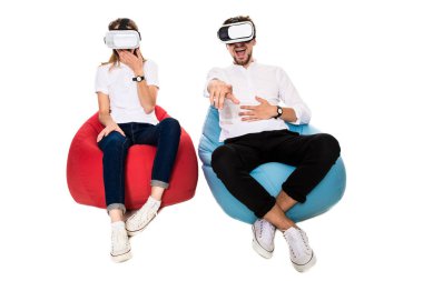 Sanal gerçeklik beyaz arka plan üzerinde izole beanbags üzerinde oturmuş yaşandığı heyecanlı genç Çift