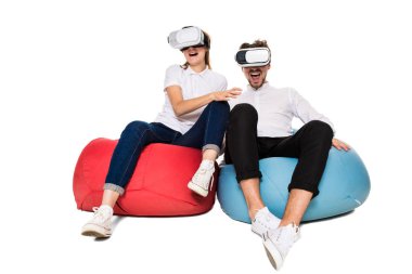 Sanal gerçeklik beyaz arka plan üzerinde izole beanbags üzerinde oturmuş yaşandığı heyecanlı genç Çift