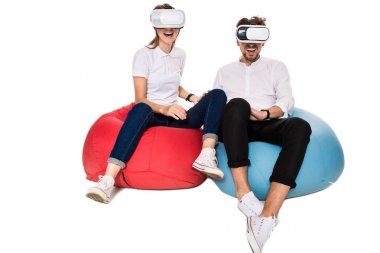 Sanal gerçeklik beyaz arka plan üzerinde izole beanbags üzerinde oturmuş yaşandığı heyecanlı genç Çift