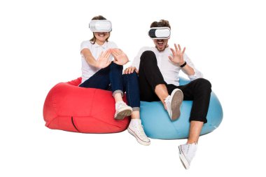 Sanal gerçeklik beyaz arka plan üzerinde izole beanbags üzerinde oturmuş yaşandığı heyecanlı genç Çift