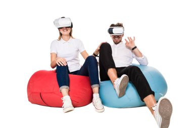 Sanal gerçeklik beyaz arka plan üzerinde izole beanbags üzerinde oturmuş yaşandığı heyecanlı genç Çift