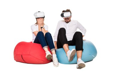 Sanal gerçeklik beyaz arka plan üzerinde izole beanbags üzerinde oturmuş yaşandığı heyecanlı genç Çift