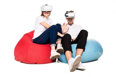 Sanal gerçeklik beyaz arka plan üzerinde izole beanbags üzerinde oturmuş yaşandığı heyecanlı genç Çift