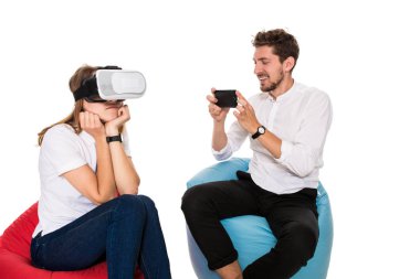 Sanal gerçeklik beyaz arka plan üzerinde izole beanbags üzerinde oturmuş yaşandığı heyecanlı genç Çift