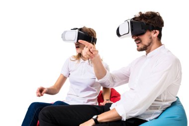 Sanal gerçeklik beyaz arka plan üzerinde izole beanbags üzerinde oturmuş yaşandığı heyecanlı genç Çift