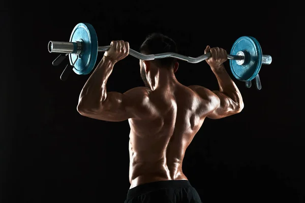 Bodybuilder lifting a barbell on black background — Stock Photo, Image