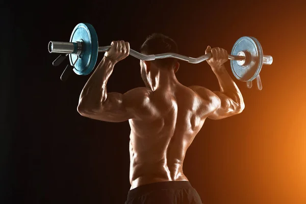 Bodybuilder lifting a barbell on black background — Stock Photo, Image
