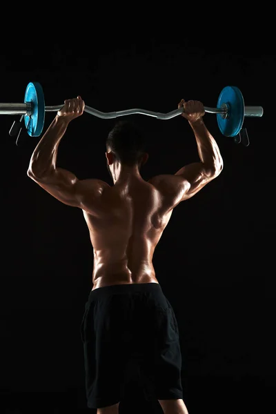 Bodybuilder lifting a barbell on black background — Stock Photo, Image