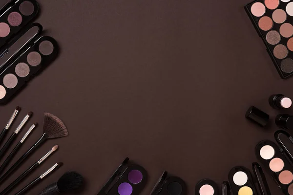 Färgstarka kosmetika på brun arbetsplats med kopia utrymme. Cosmetics göra upp konstnären föremål: läppstift, ögonskuggor, puder, verktyg för make-up. Ovanifrån. — Stockfoto