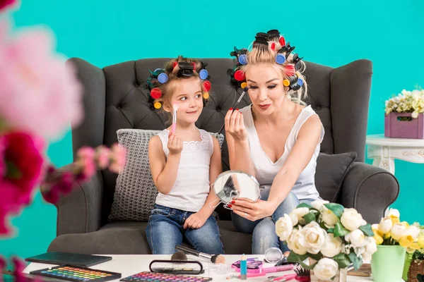 Anne ve kızı curlers içinde kanepede stüdyoda makyaj ve iyi eğlenceler