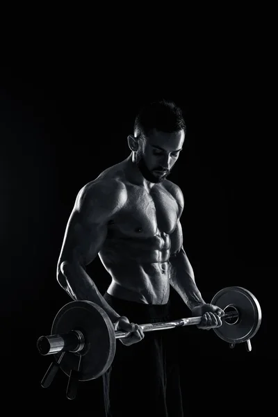 Homem muscular levantando pesos sobre fundo escuro — Fotografia de Stock