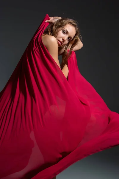暗い灰色スタジオ背景にポーズをとって赤いドレスの若い美しいダンサー — ストック写真