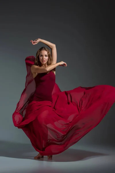 暗い灰色スタジオ背景にポーズをとって赤いドレスの若い美しいダンサー — ストック写真