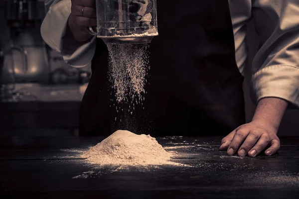 As mãos do chef estão deixando cair farinha sobre uma mesa de madeira — Fotografia de Stock