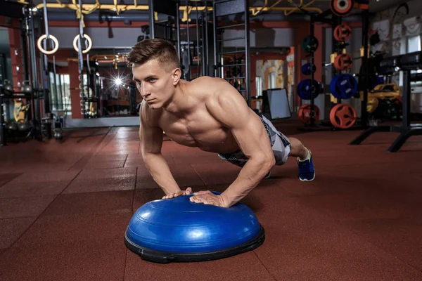 Kaslı adam bosu topu crossfit spor salonunda itme yapıyor