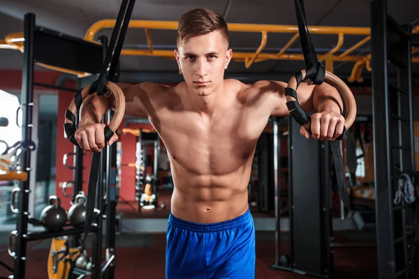 Portret van jonge man met gymnastiek ringen tijdens het sporten in de sportschool — Stockfoto