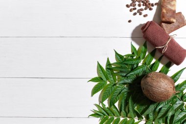 Kahve çekirdekleri, kahverengi havlu, Hindistan cevizi ve Beyaz ahşap zemin üzerine yeşil yaprakları ile doğal el yapımı sabunlar